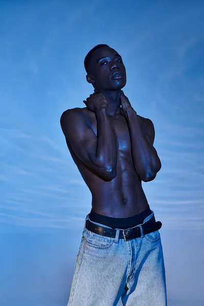 Engageant homme noir américain torse nu en jeans à la mode en regardant la caméra sur fond aqueux — Photo de stock