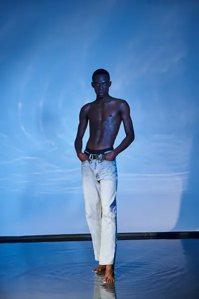 Tempting shirtless african american man in fashionable jeans looking at camera on watery backdrop — Stock Photo