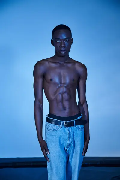 Handsome shirtless african american man in fashionable jeans looking at camera on watery backdrop — Stock Photo