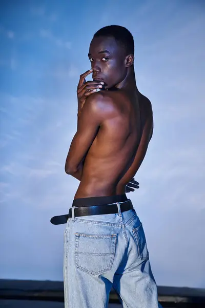 Alluring shirtless african american man in fashionable jeans looking at camera on watery backdrop — Stock Photo