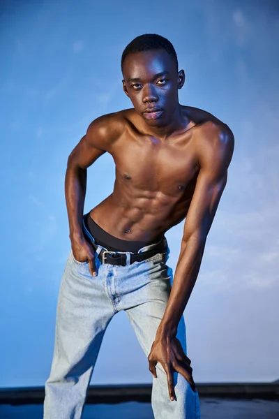 Handsome shirtless african american man in blue jeans looking at camera on watery background — Stock Photo