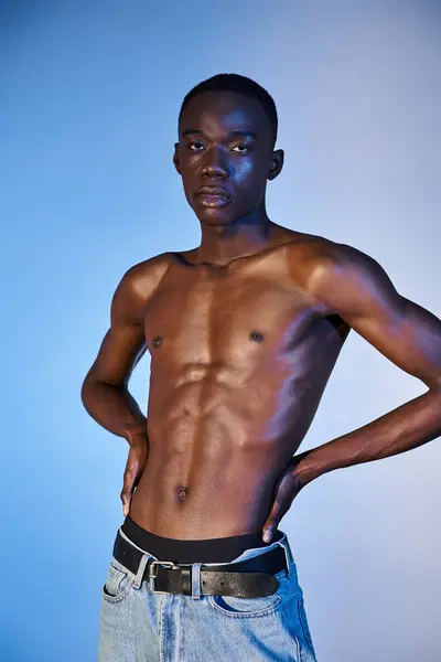 Shirtless trendy african american man in modern jeans and looking at camera on blue background — Stock Photo