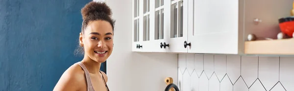 Joyous beautiful african american woman in homewear smiling happily at camera in kitchen, banner — Stock Photo