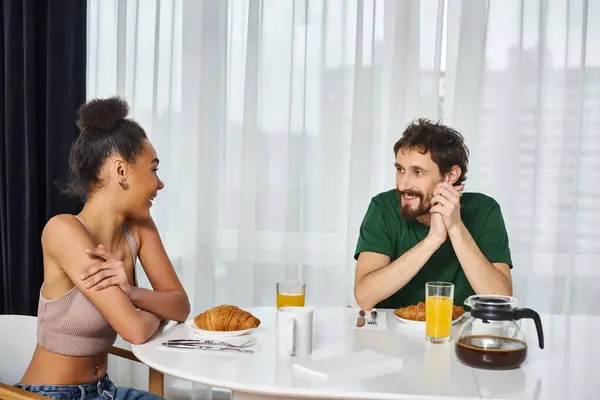 Appealing beautiful interracial couple in casual outfits enjoying their delicious breakfast at home — Stock Photo