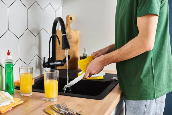 Cropped view of man in casual homewear washing plate with cleanser in sink while in kitchen at home — Stock Photo