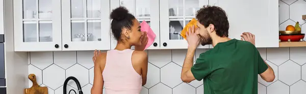 Jolly attractive multiracial girlfriend and boyfriend in comfy homewear doing chores in kitchen — Stock Photo