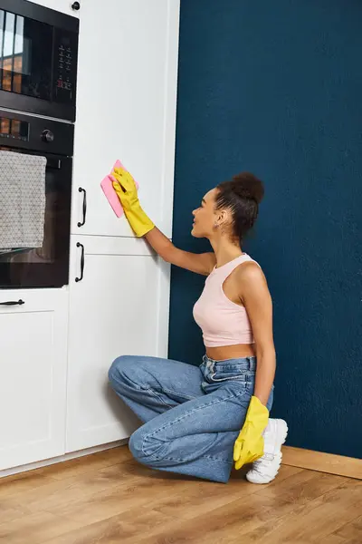 Jolly bella donna africana americana in abbigliamento casual lavaggio bancone della cucina, pulizia primaverile — Foto stock