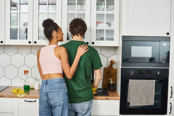 Jolly beautiful african american woman looking happily at her loving boyfriend doing his chores — Stock Photo