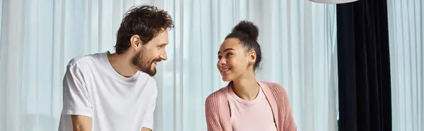 Joyous good looking multiracial couple in cozy homewear smiling happily at each other, banner — Stock Photo