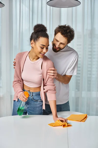 Good looking multiracial jolly couple in homewear cleaning together at home and smiling happily — Stock Photo