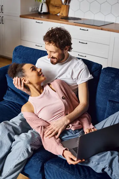 Good looking cheerful diverse couple watching movies on their laptop and looking at each other — Stock Photo