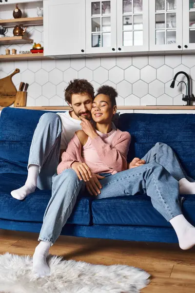 Good looking contented couple in comfortable homewear hugging warmly on sofa while at home — Stock Photo