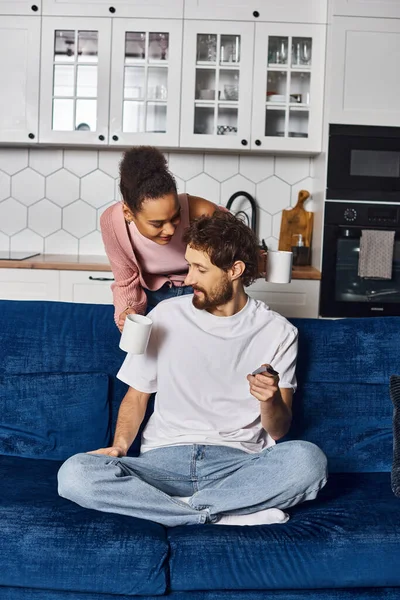 Atractiva mujer afroamericana en traje casual sugiriendo taza de café a su novio guapo — Stock Photo