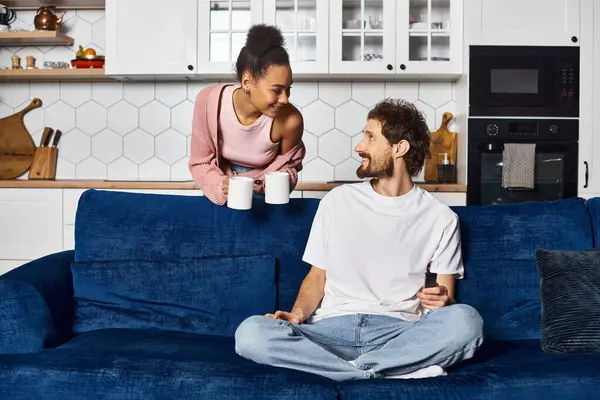 Appealing cheerful diverse couple spending time together and drinking coffee, smiling at each other — Stock Photo