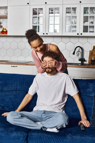 Beautiful jolly african american woman closing eyes of her handsome boyfriend with her hands — Stock Photo