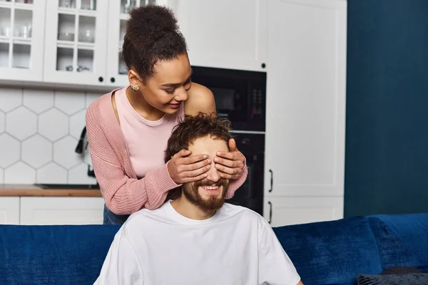 Appealing joyous african american woman closing her boyfriend eyes with hands to surprise him — Stock Photo