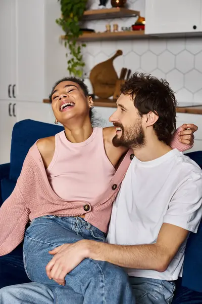 Joyous african american woman sitting on laps of her handsome boyfriend and laughing sincerely — Stock Photo