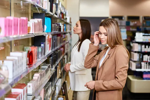 Joyful attractive women in business casual attires choosing new perfumes in cosmetics store — Stock Photo