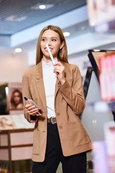 Beautiful blonde woman in stylish sophisticated attire choosing new perfumes in cosmetics store — Stock Photo