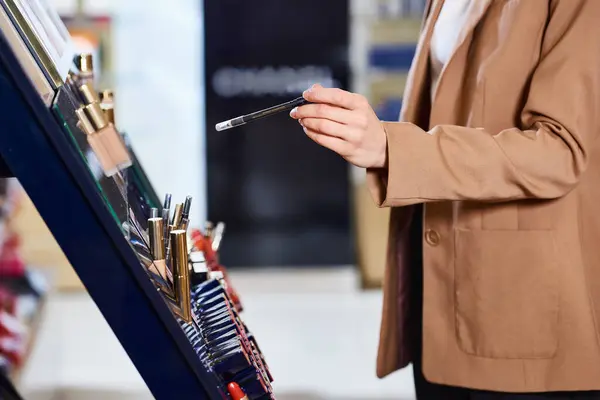Cropped view of caucasian woman in business casual picking new lipstick while in cosmetics store — Stock Photo