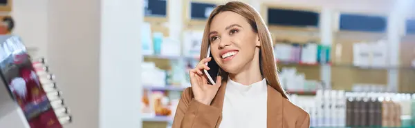 Gut aussehende fröhliche Frau in trendiger Kleidung, die im Kosmetikgeschäft telefoniert, Banner — Stockfoto