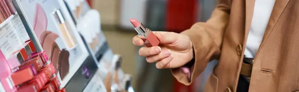 Cropped view of sophisticated woman choosing new pink lipstick while in cosmetics store, banner — Stock Photo