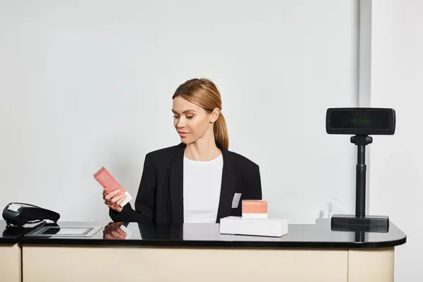 Good looking shop assistant in sophisticated black blazer sitting at counter and looking at perfumes — Stock Photo