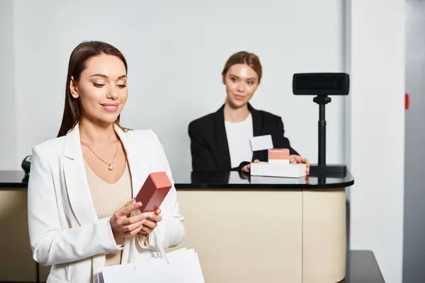 Cheerful beautiful female customer holding perfumes next to shop assistant in cosmetics store — Stock Photo