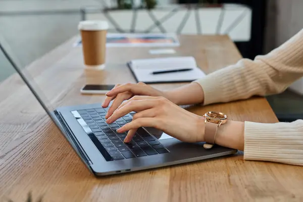 Целенаправленная деловая женщина, печатающая на ноутбуке за гладким деревянным столом в современном офисе, воплощая концепцию франшизы. — стоковое фото