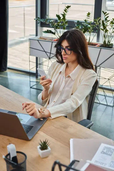 A businesswoman sits at a table in a modern office, using a laptop to work on franchise concepts. — Stock Photo