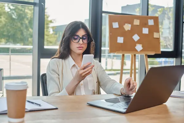 Une femme d'affaires est assise devant un ordinateur portable dans un bureau moderne, se concentrant sur son travail et la gestion de sa franchise. — Photo de stock