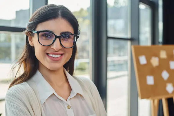 A happy businesswoman wearing glasses in a modern office setting. — Stock Photo