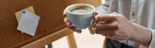 Современная деловая женщина берет перерыв на кофе в своем офисе, держа в руке чашку свежеприготовленного кофе. — стоковое фото