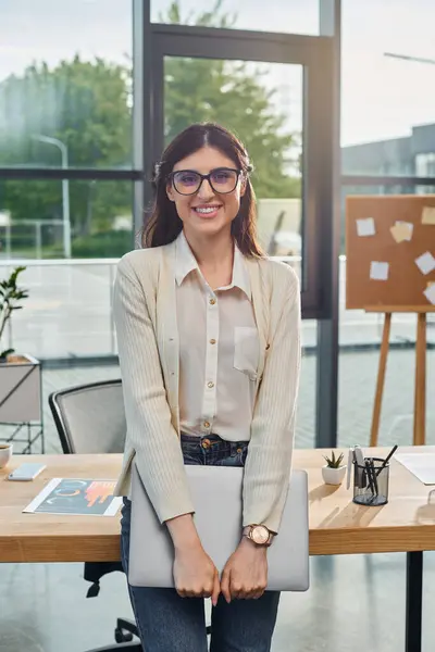 A businesswoman sits at a table with a laptop in a modern office, embodying the franchise concept. — Stock Photo