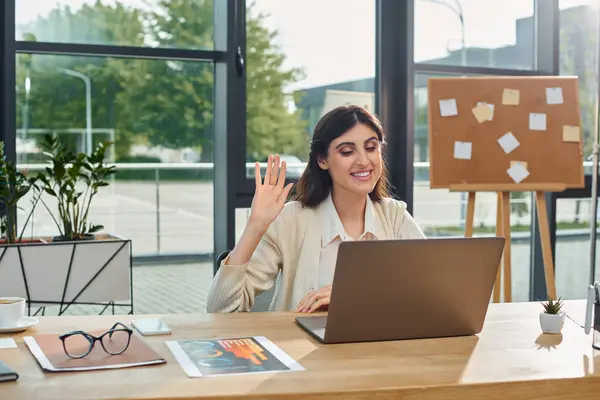 Una mujer de negocios en una oficina moderna se sienta frente a una computadora portátil, profundamente pensada mientras trabaja en un concepto de franquicia. - foto de stock