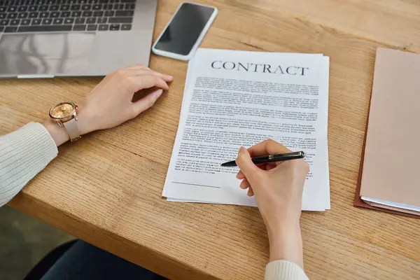 Une femme d'affaires dans un bureau moderne assis à une table, axée sur la signature d'un contrat lié à un concept de franchise. — Photo de stock