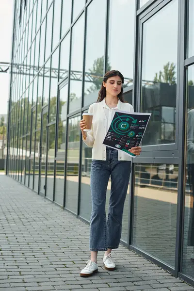 A modern businesswoman stands outside a building, holding charts, embodying the concept of growth and learning in a franchise setting. — Stock Photo