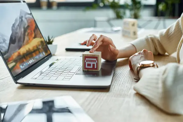 A modern businesswoman holds a small house model in front of a laptop, embodying innovation in franchise concepts. — Stock Photo