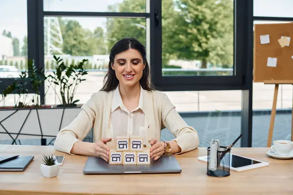 Una mujer de negocios se sienta en una mesa, centrada en bloques en un entorno de oficina moderno, encarnando el concepto de franquicia. - foto de stock