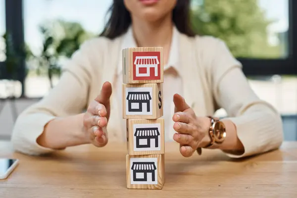 A businesswoman sits at a table, engaging in a franchise concept, with a stack of blocks representing growth and innovation. — Stock Photo