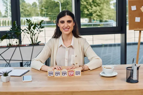 Une femme d'affaires assise à une table, entourée de blocs, réfléchissant à son prochain mouvement dans le monde des franchises. — Photo de stock