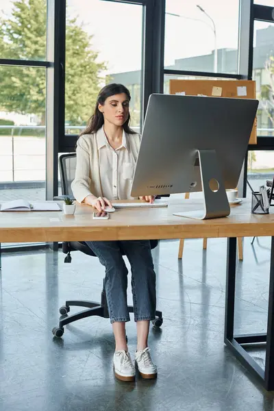 Uma empresária focada senta-se em uma mesa elegante, absorvida em sua tela de computador, incorporando o conceito de franquia moderna. — Fotografia de Stock