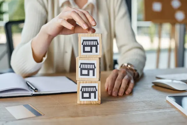 Une femme d'affaires dans un bureau moderne empile des blocs sur une table en bois, représentant le concept d'une franchise. — Photo de stock