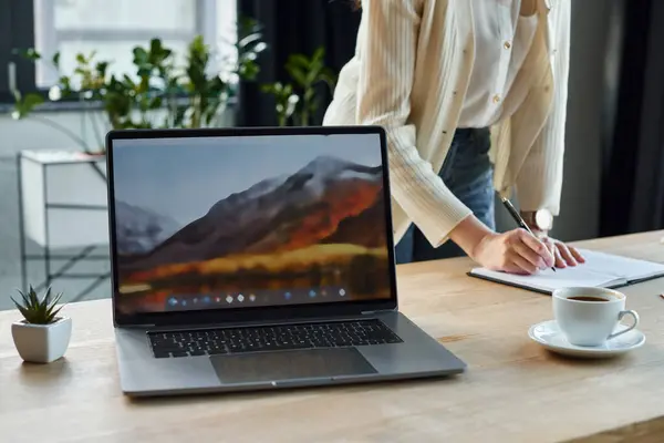 Una donna d'affari concentrata che utilizza un computer portatile su un tavolo di legno in un ambiente ufficio moderno, incarnando il concetto di franchising. — Foto stock