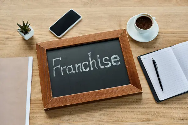 Eine Tafel mit dem Wort Franchise neben einer Tasse Kaffee in einem modernen Büroumfeld. — Stockfoto