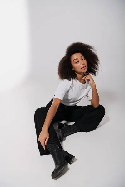 Attraente afro-americana modello femminile seduto sul pavimento e guardando la fotocamera, concetto di moda — Foto stock