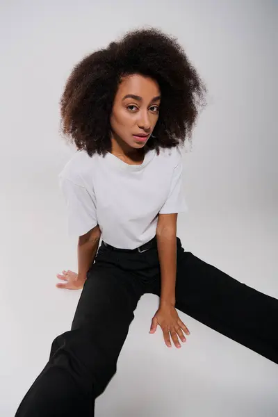 Beautiful african american female model sitting on floor and looking at camera, fashion concept — Stock Photo