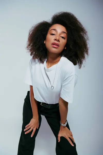 Appealing african american woman in chic attire with curly hair looking at camera, fashion concept — Stock Photo