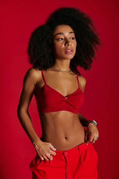 Sexy alluring african american woman in red vibrant bra posing on red background and looking away — Stock Photo