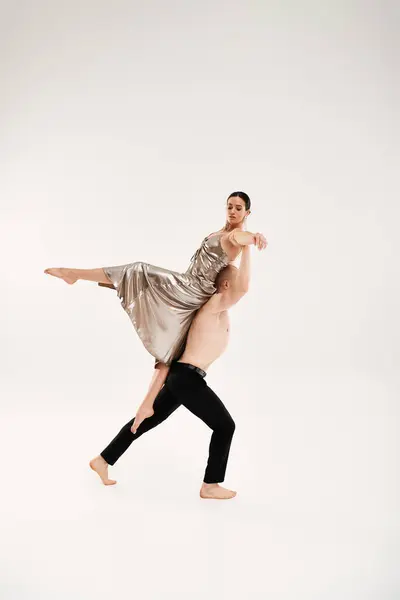 Shirtless joven hombre y mujer en vestido brillante ejecutando movimientos acrobáticos de baile sobre fondo blanco - foto de stock